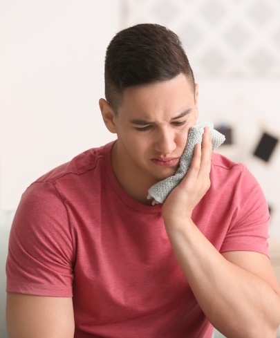 Man holding cold compress to face after traumatic dental injuries