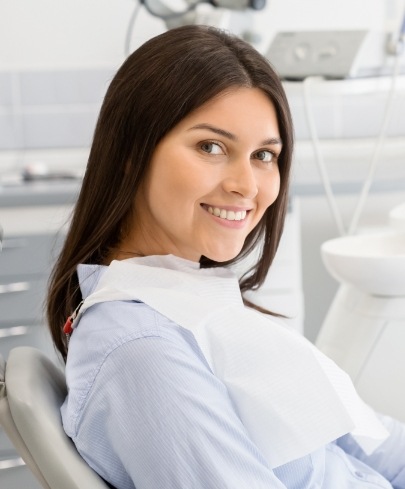 Woman in dental chair smiling after endodontic retreatment