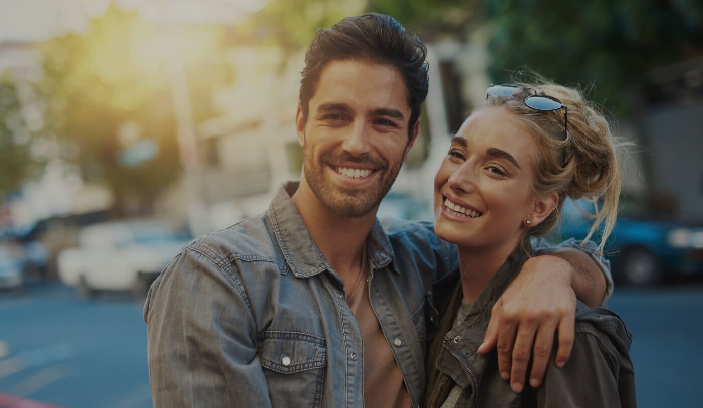 Couple sharing happy smiles after visiting their endodontist in Worcester Massachusetts