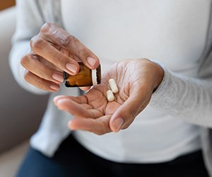 Closeup of woman putting white pills into her hands