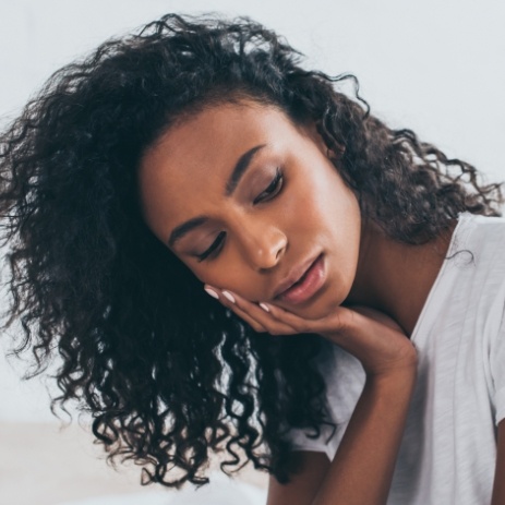 Woman in need of root canal therapy holding cheek in pain