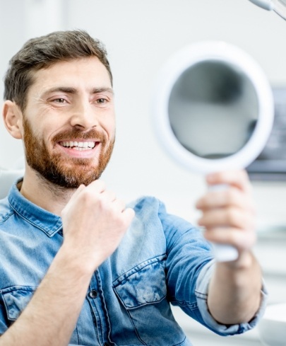 Man looking at smile in mirror after endodontic services