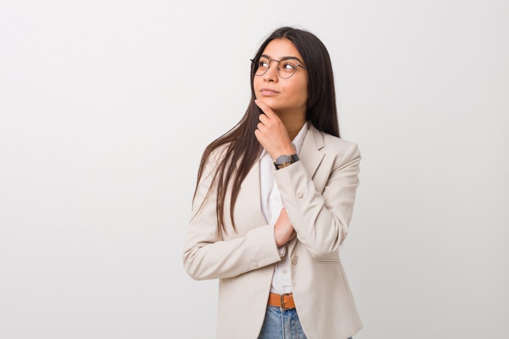 Woman with glasses and blazer wondering