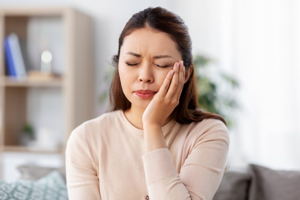 Woman experiencing tooth pain at home