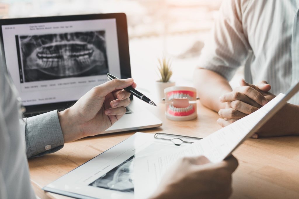 Endodontist reviewing paperwork and X-ray with patient