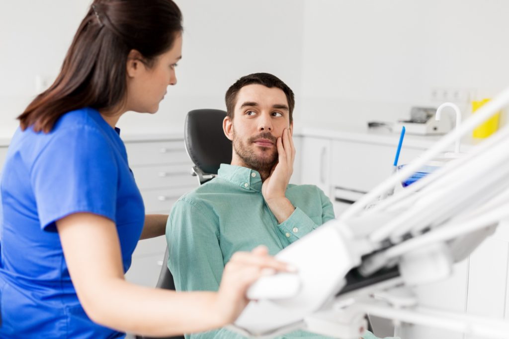 Man with tooth pain talking to endodontist in office